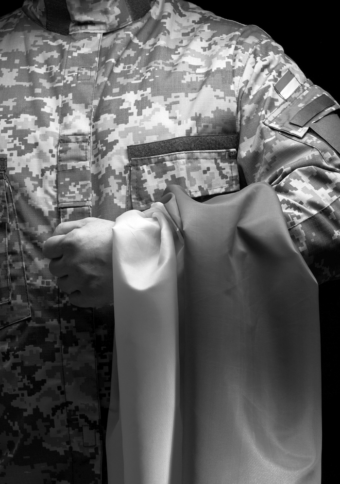 a soldier of the Ukrainian armed forces stands with a blue-yellow flag of Ukraine on a black background. Honoring veterans and commemorating those killed in the war